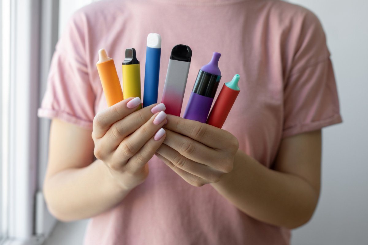 Faceless woman holding several vape and e-cig devices