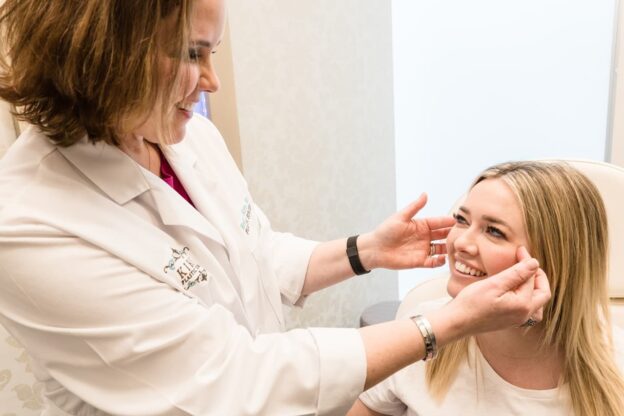Plastic surgeon Fort Worth in white coat examines a patient's face